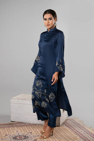 Woman wearing a navy blue dress with floral patterns on a plain background