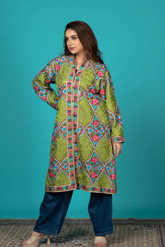 Woman wearing a colorful embroidered kurta with blue pants against a teal background