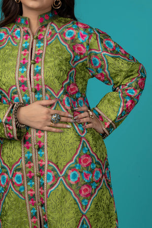 Green embroidered dress with pink and blue patterns on a teal background