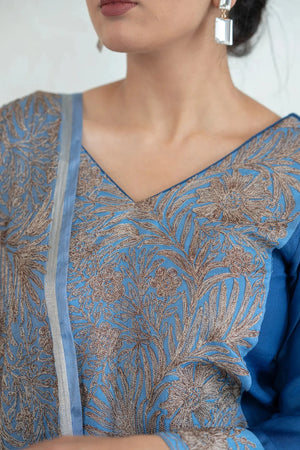 Close-up of a blue and silver embroidered traditional outfit with a plain background
#AquaBlue